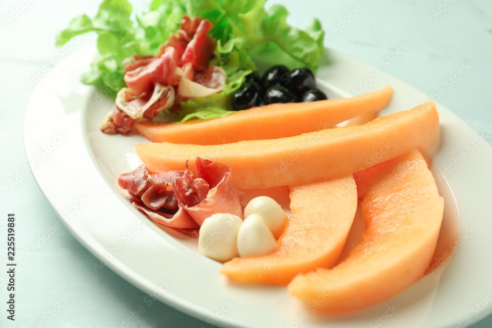 Delicious melon with prosciutto and mozzarella on plate, closeup