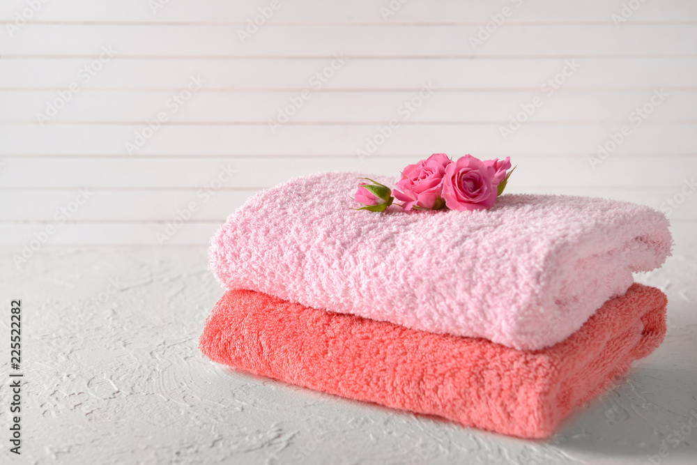 Stack of clean soft towels with flowers on white table