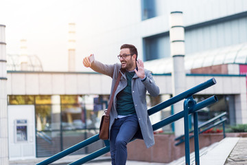 Wall Mural - Smiling young modern businessman making video conversation via smartphone