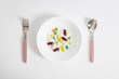 Various colorful pills on white plate and fork and spoon