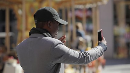 Wall Mural - Black man with smartphone online video broadcasting in city