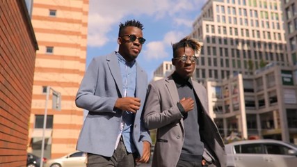 Wall Mural - Two young friends businessmen walking and talking in city downtown