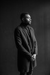 © sofiko14 - Attractive man in coat on dark background. Professional photo studio. Fashion portrait of young man in black shirt in studio. black and white portrait