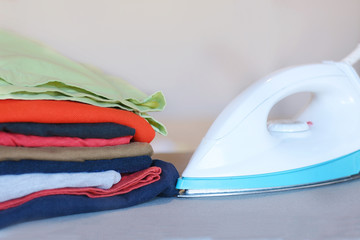 Wall Mural - Close up view of iron clothes on ironing board with stack of ironed shirts