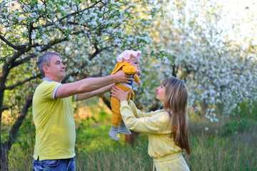 The father passes the daughter to her mother in a flowering garden