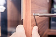 Fasten The Screw Of A Doorhandle Of A Brown Cupboard With A Screwdriver, DIY Concept