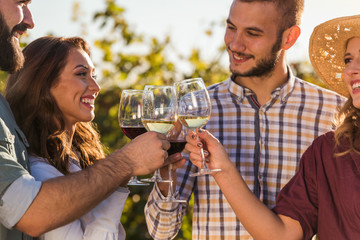 Happy friends having fun drinking wine at winery vineyard - Friendship concept with young people enjoying harvest time together