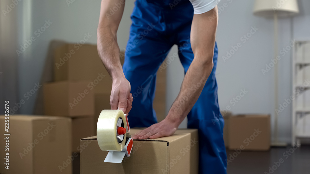 Moving company worker packing cardboard boxes, quality delivery services - obrazy, fototapety, plakaty 
