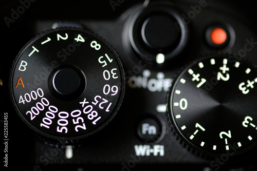 Fotomural Shutter Speed dial of a digital camera in black background.