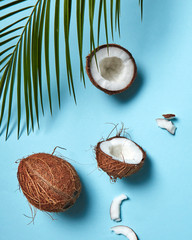 Wall Mural - Pieces and whole coconut with palm green leaf on a blue background copy space for text. Food composition. Flat lay