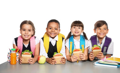 Poster - Schoolchildren with healthy food and backpacks sitting at table on white background