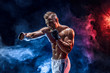 © zamuruev - Studio portrait of fighting muscular man in smoke on dark background