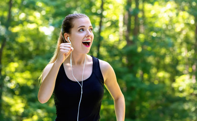 Wall Mural - Athletic young woman jogging on a bright summer day in the forest