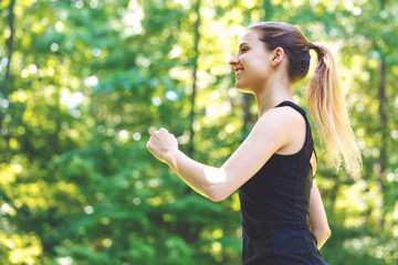 Wall Mural - Athletic young woman jogging on a bright summer day in the forest