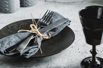 Wall Mural - Festive table setting in a black style among black candles. Plate with fork and knife on a linen napkin. Thanksgiving or Halloween dinner.