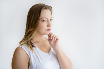 Sticker - Pensive young woman looking at camera. Pretty lady standing and touching chin. Contemplation concept. Isolated side view on white background.