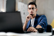 © Leika production - Dark-haired young architect in glasses dressed in blue checkered jacket  works on the laptop in the office