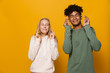 © Drobot Dean - Photo of teenage friends man and woman 16-18 keeping fingers crossed and dreaming for good luck, isolated over yellow background