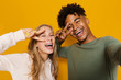 Photo closeup of joyful students man and woman 16-18 having fun and taking selfie, isolated over yellow background