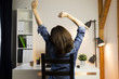Woman stretching her arms sitting by the table at work next to computer. Working late concept