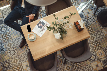 Wall Mural - overhead view of businessman in suit at table with newspaper, cup of coffee and smartphone in cafe