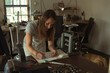 © Wavebreak Media - Jewelry designer writing on a register in workshop