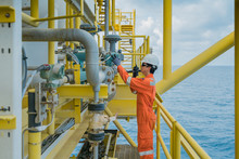 Offshore Oil And Gas Worker Operating Touch Screen Of Gas Flow Meter Coriolis Type To Reading And Adjusting Parameter Of Flow Element And Used Radio To Talk With Central Control Room Operator.