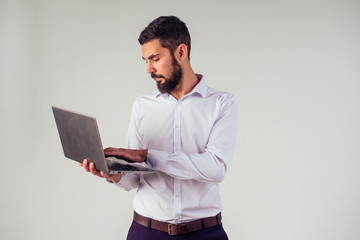 male office worker smiling and holding a laptop in his hand on a white background in the studio