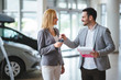 © NDABCREATIVITY - Woman is talking to handsome car dealership worker while choosing a car