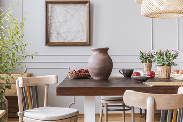 Wall Mural - Wooden chairs at table with vase and flowers in grey dining room interior with poster. Real photo