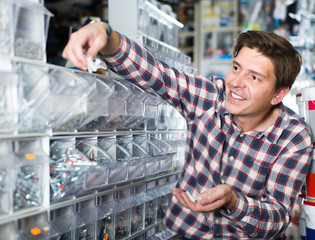 Wall Mural - Adult man buyer looking switches for light and sockets in the shop