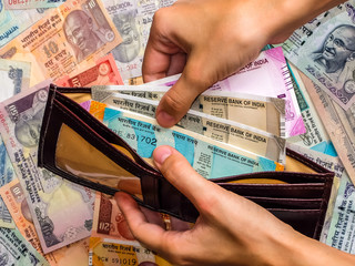 Woman's hands holding wallet with indian notes. 10, 20, 50, 100, 200, 500 and 2000 Indian rupees, old and new notes.