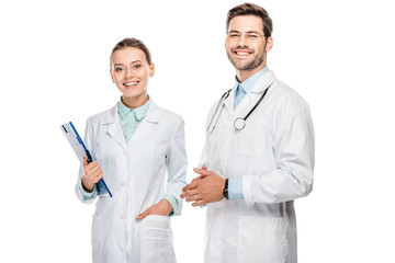 Wall Mural - happy female doctor holding clipboard while her male colleague standing near isolated on white