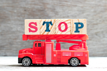 Wall Mural - Toy fire ladder truck hold letter block in word stop on wood background