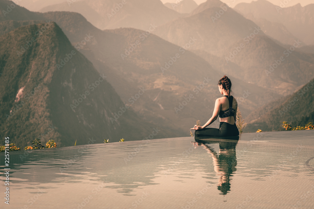 Beautiful Attractive Asian woman practice yoga Lotus pose on the pool above the Mountain peak in the morning in front of beautiful nature views,Feel so comfortable and relax in holiday,Warm Tone - obrazy, fototapety, plakaty 