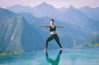© 220 Selfmade studio - Beautiful Attractive Asian woman practice yoga warrior or Virabhadrasana Pose on the pool above the Mountain peak in the morning in front of beautiful nature views in SAPA vietnam,Feel so comfortable