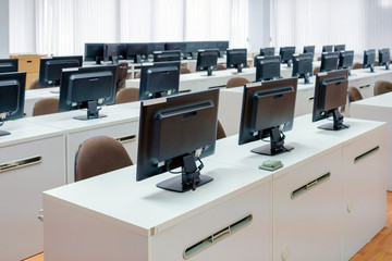 classroom computers. empty no people with many monitor computer on white desk.