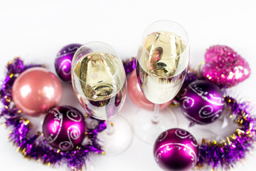 Two champagne glass with purple christmas toys on white background.