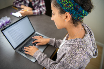 High school student girl learning online, doing research, and working on homework using a laptop computer