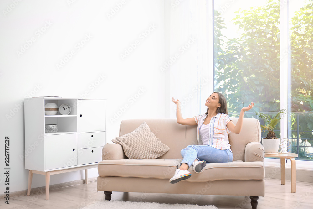 Young woman relaxing under air conditioner at home - obrazy, fototapety, plakaty 
