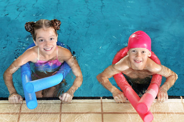 Wall Mural - Little kids with swimming noodles in indoor pool