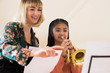 © Daisy Daisy - Teacher Helping Female Student To Play Trumpet In Music Lesson