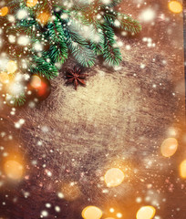Wall Mural - christmas tree background with pine tree branch, decoration and sparkling lights on dark wooden boar