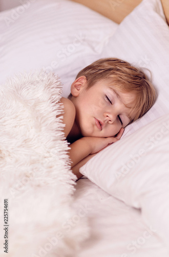 A Little Boy Is Sleeping In A White Crib Pore Goes To Bed Good