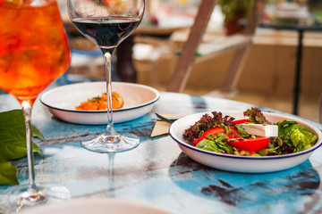 A delicious salad with greens on the table in the cafe. Salad on a white plate