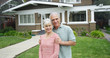 © Mark Adams - Senior couple standing smiling in front of new home