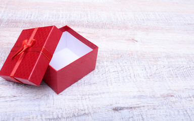 Wall Mural - Red gift box with ribbon bow opened on vintage white wooden table