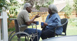 © Mark Adams - Disabled elderly African man talking with wife in the backyard