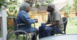 © Mark Adams - Senior African woman in wheel chair outdoors with husband