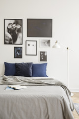 Wall Mural - White industrial style floor lamp by a cozy bed with dark blue cushions in a bright hipster bedroom interior